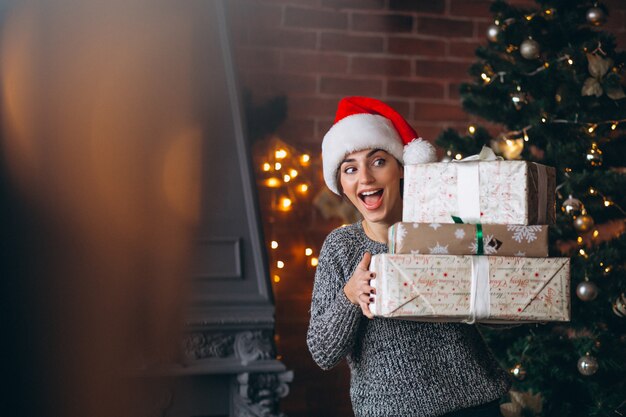 Donna con regali in piedi davanti all&#39;albero di Natale