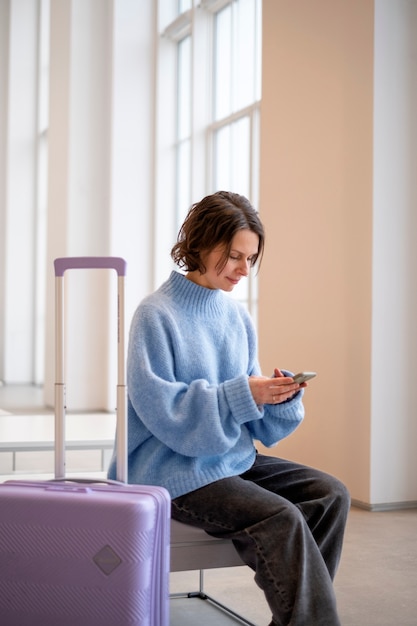 Donna con smartphone e bagagli nella hall dell'hotel