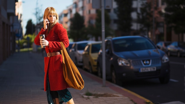 Donna con smartphone e bevande in strada