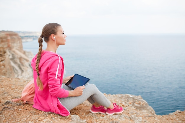 donna con tablet in tuta sportiva in riva al mare