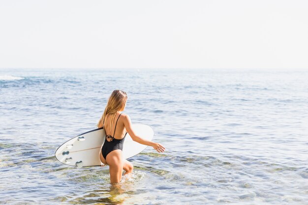 Donna con tavola da surf in spiaggia