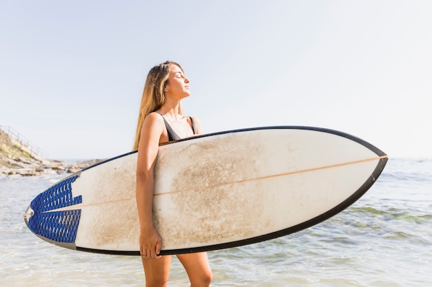 Donna con tavola da surf in spiaggia