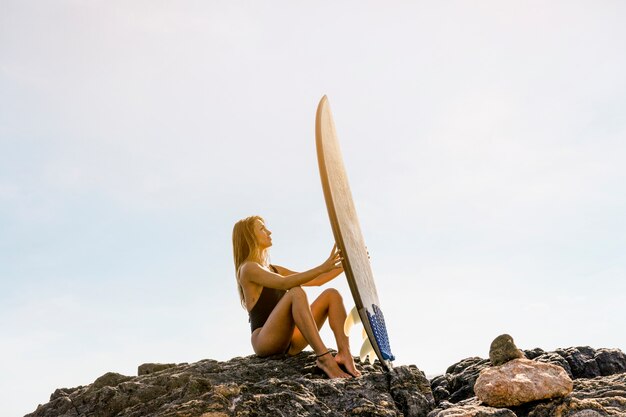 Donna con tavola da surf in spiaggia