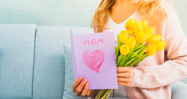 Donna con tulipani e cartolina per la festa della mamma