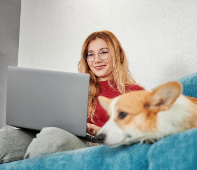 Donna con un adorabile animale domestico che lavora o studia nel laptop a casa