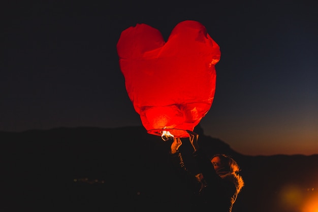 Donna con un aquilone di aria calda di notte