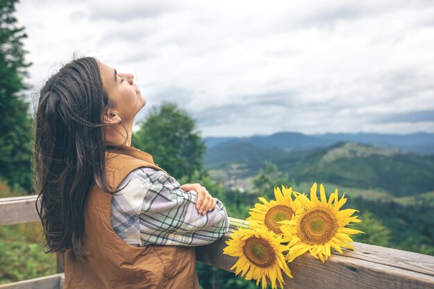 Donna con un mazzo di girasoli in natura in montagna