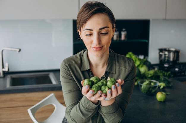 Donna con un mazzo di verdure verdi in cucina