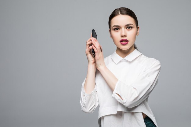 Donna con un telefono cellulare. Isolato sul muro bianco.