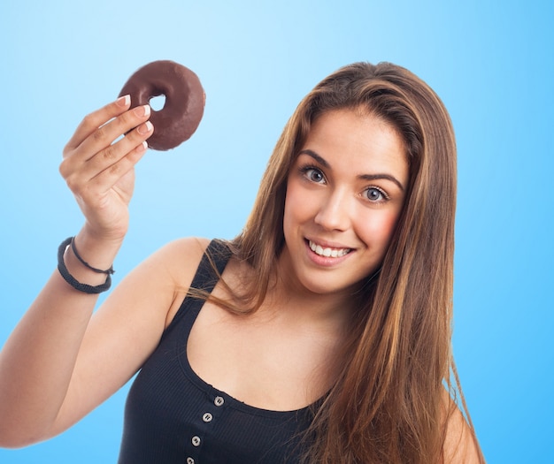 Donna con una ciambella al cioccolato in una mano