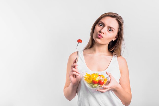 Donna con una ciotola di insalata che soffia un bacio