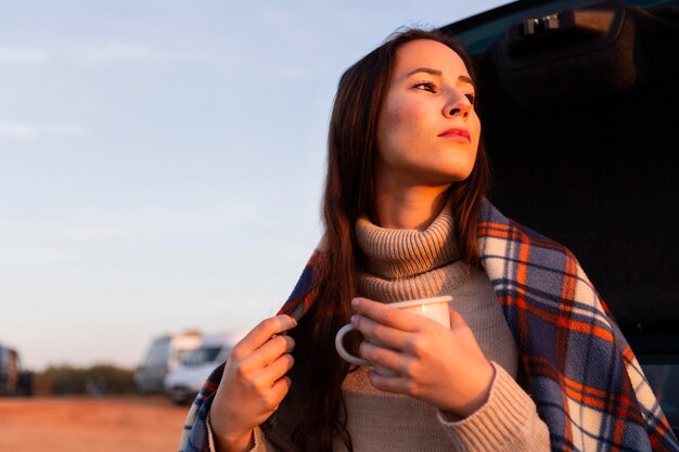 Donna con una coperta all'aperto godendo di una tazza di caffè