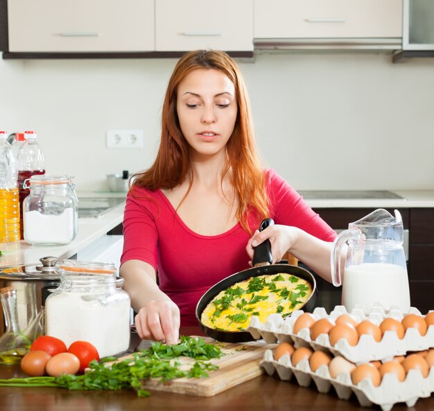 donna con uova strapazzate in padella a casa