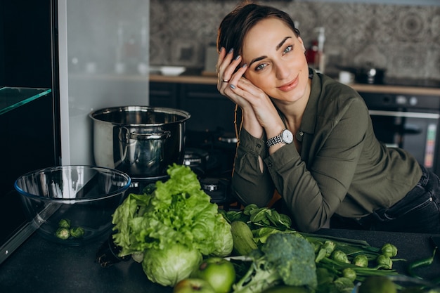 Donna con verdure verdi in cucina