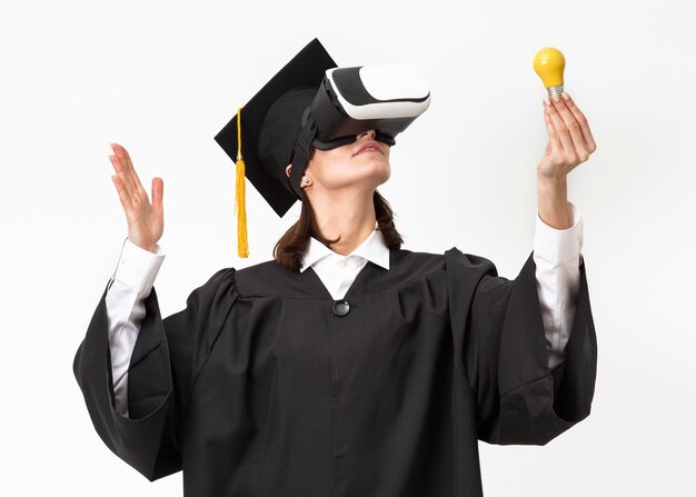 Donna con veste di laurea e berretto che indossa le cuffie da realtà virtuale