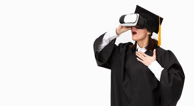 Donna con veste di laurea e berretto che indossa le cuffie da realtà virtuale