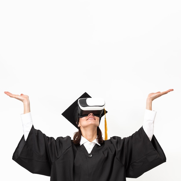 Donna con veste di laurea e berretto che indossa le cuffie da realtà virtuale