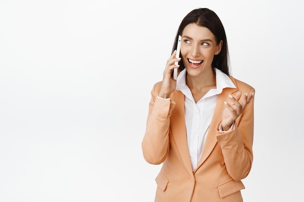 Donna corporativa di successo che parla sul telefono cellulare che fa affare su chiamata in piedi su sfondo bianco
