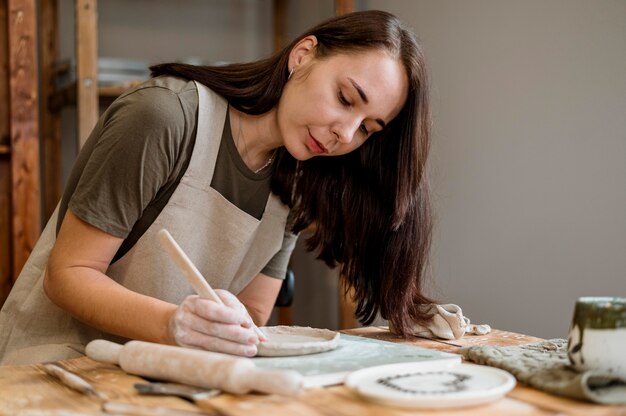 Donna creativa che fa una pentola di creta nel suo laboratorio