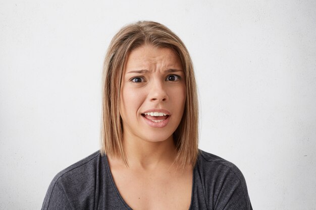 Donna cupa e stupita con i capelli tinti che guarda con gli occhi spuntati e la bocca aperta, le sopracciglia accigliate che sono sorprese