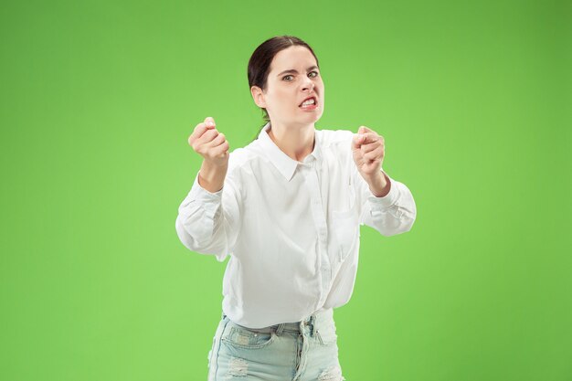 Donna d'affari aggressiva in piedi isolato sulla parete verde alla moda dello studio