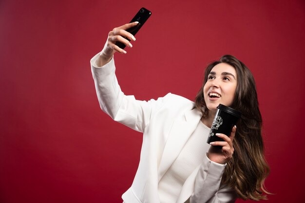 Donna d'affari che cattura un selfie con una tazza di caffè