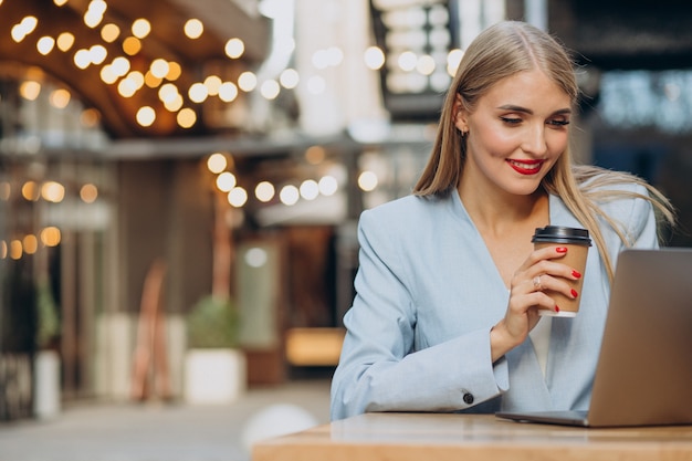 Donna d'affari che lavora al computer in un bar e beve caffè