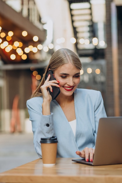 Donna d'affari che lavora al computer in un bar e beve caffè