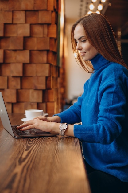 Donna d'affari che lavora al computer portatile in un bar