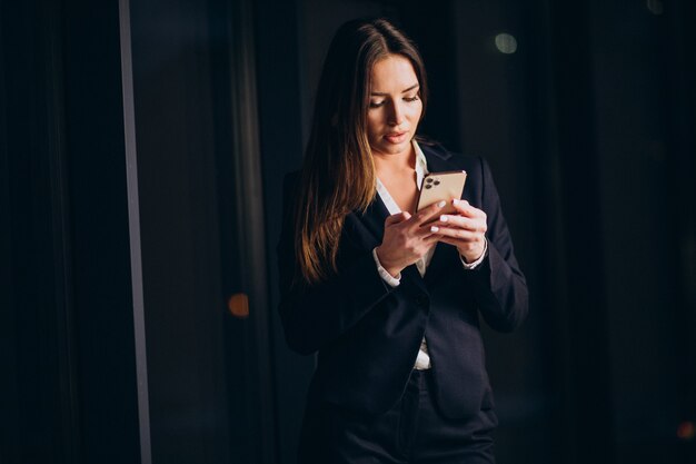 Donna d'affari che parla al telefono e resta fino a tarda notte in ufficio