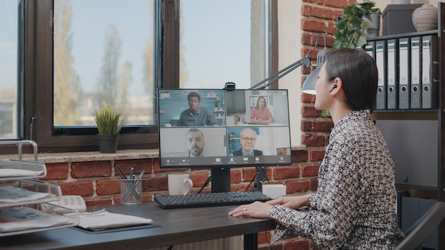 Donna d'affari che parla con i colleghi durante una videochiamata online, svolgendo un lavoro di squadra sulla pianificazione del progetto. Persona che utilizza la videoconferenza remota per conversare sullo sviluppo. Teleconferenza