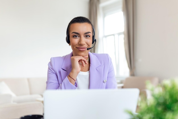 Donna d'affari con cuffie che lavora con il computer in ufficio Assistente del servizio clienti che lavora in ufficio Operatore che lavora con cuffie e laptop al call center del servizio clienti di telemarketing