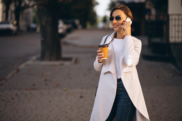 Donna d&#39;affari con telefono bere caffè fuori in strada