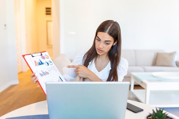 Donna d'affari concentrata che presenta grafici e grafici durante la videochiamata online Giovane donna d'affari che ha una chiamata in conferenza con il cliente sul laptop Donna d'affari di primo piano che lavora computer portatile al coperto