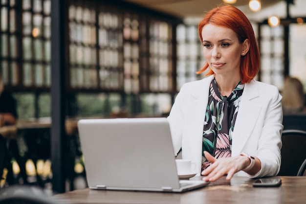 Donna d'affari di successo che lavora al computer portatile in un caffè