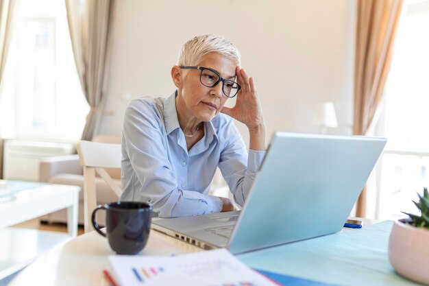 Donna d'affari matura preoccupata di pensare al problema online Donna di mezza età preoccupata frustrata che soffre di perdita di memoria