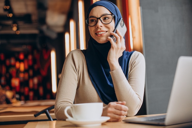 Donna d'affari musulmana che lavora al computer in un caffè