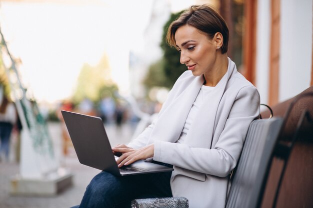 Donna d&#39;affari seduto su una panchina e lavorando su un computer