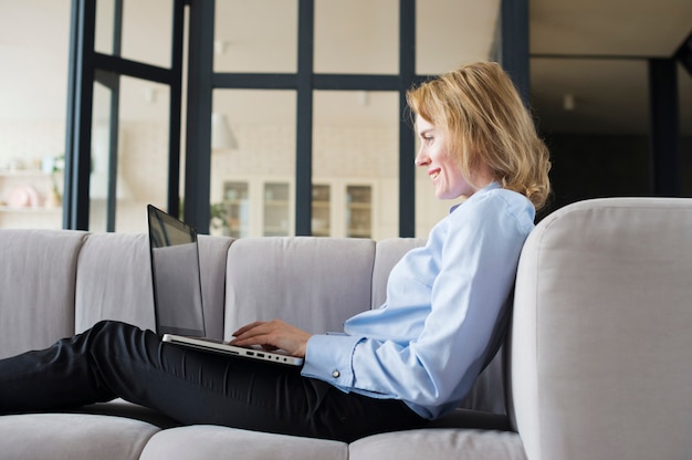 Donna d&#39;affari utilizzando il computer portatile sul divano