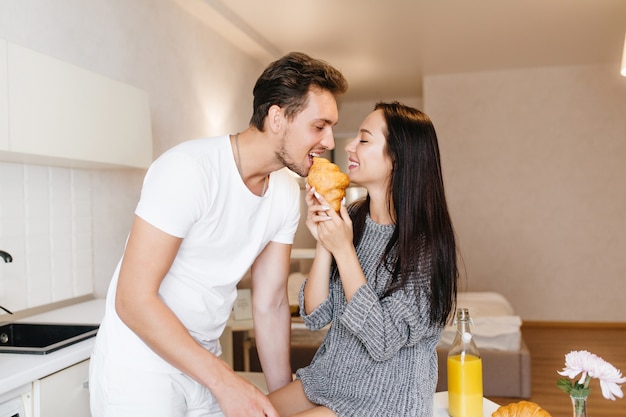 Donna dai capelli lunghi che alimenta il ragazzo con croissant e sorridente