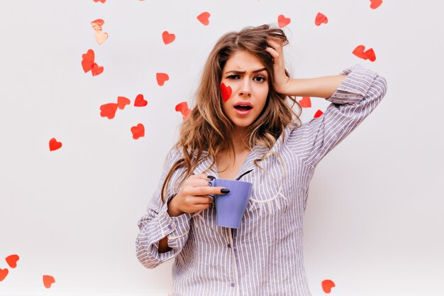 Donna dai capelli lunghi sonnolenta che gode del caffè al mattino