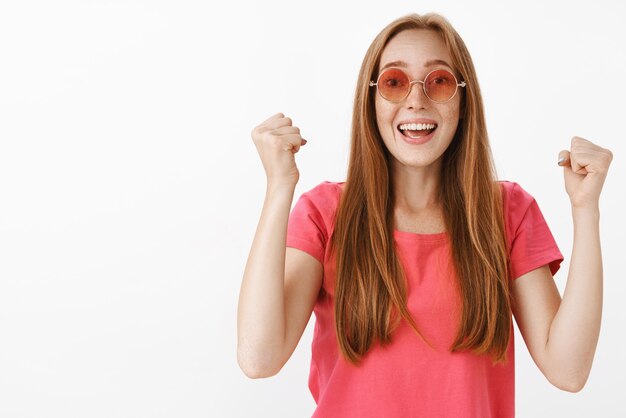 Donna dai capelli rossi che applaude, alzando i pugni in alto nella mossa di supporto sorridendo con gioia urlando continua a cercare di aumentare la fiducia in piedi