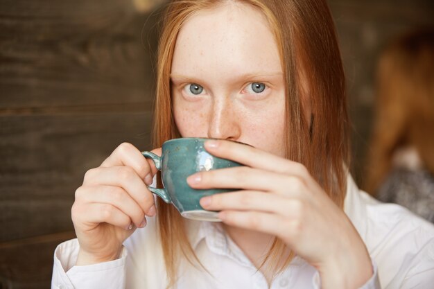 Donna dai capelli rossi che si siede nella caffetteria
