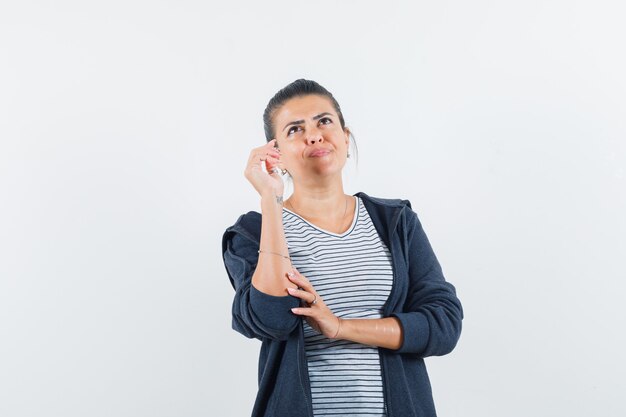 Donna dai capelli scuri che alza una mano mentre cerca in camicia