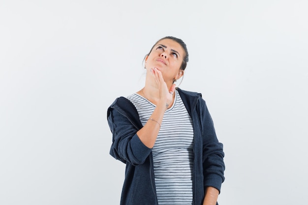 Donna dai capelli scuri che tiene la mano sul mento in camicia