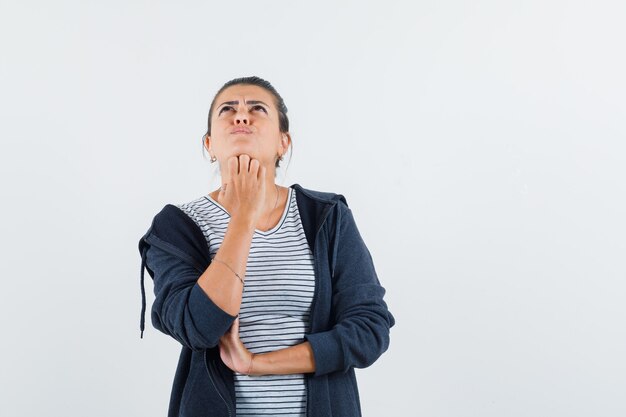 Donna dai capelli scuri che tiene la mano sulla mascella mentre cerca in camicia