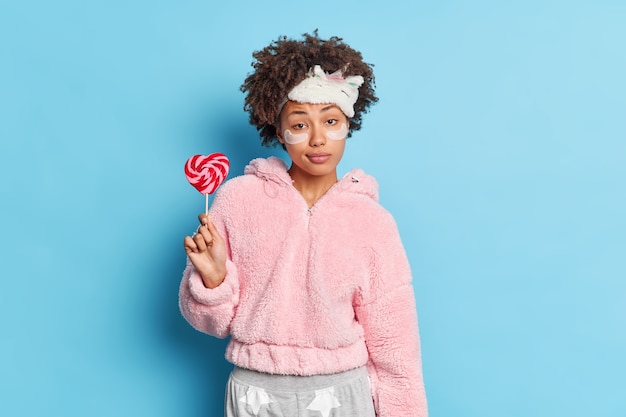 Donna dalla pelle scura seria con capelli afro ricci esamina la macchina fotografica