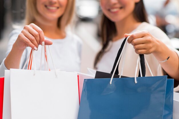 Donna defocued due che mostra molti sacchetti della spesa dopo la baldoria dello shopping