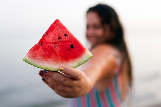 Donna defocused nell'acqua alla spiaggia che tiene anguria