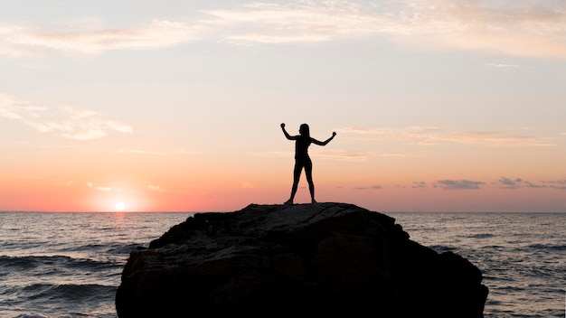 Donna del colpo lungo in abiti sportivi che si godono il tramonto con lo spazio della copia